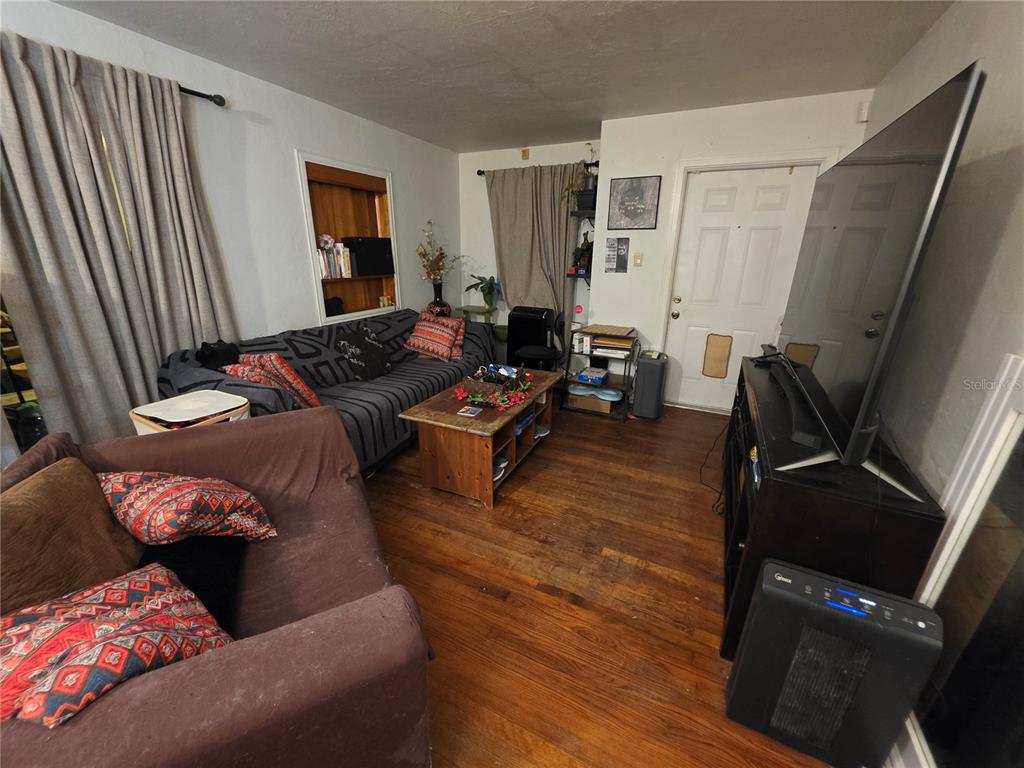 A living room features hardwood floors, two sofas, a coffee table, and a large television — 1135 W GREENWOOD STREET, LAKELAND, FL