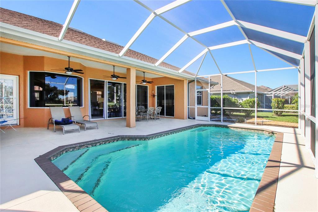 A screened-in patio features a swimming pool with steps and outdoor furniture under a roof — 2525 JASMINE WAY, NORTH PORT, FL