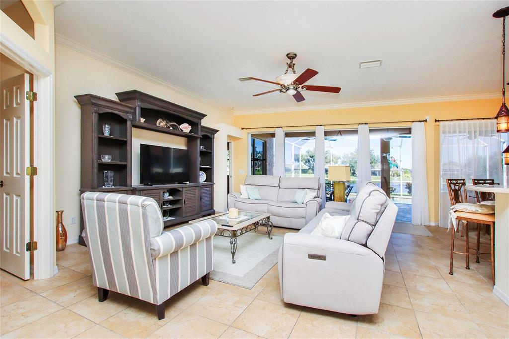 A living room with tile floors, a large entertainment center, and sliding glass doors to outside — 2525 JASMINE WAY, NORTH PORT, FL