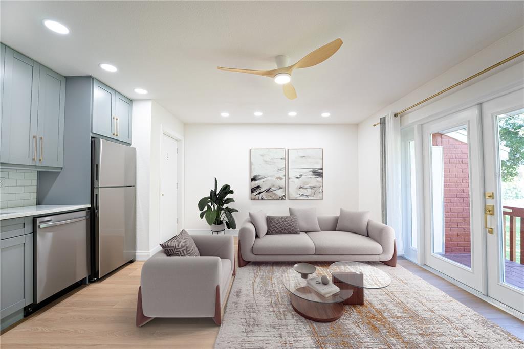 A living room with a kitchen area, light wood flooring, a sofa, and a ceiling fan — 8210 12TH WAY N UNIT G, ST PETERSBURG, FL
