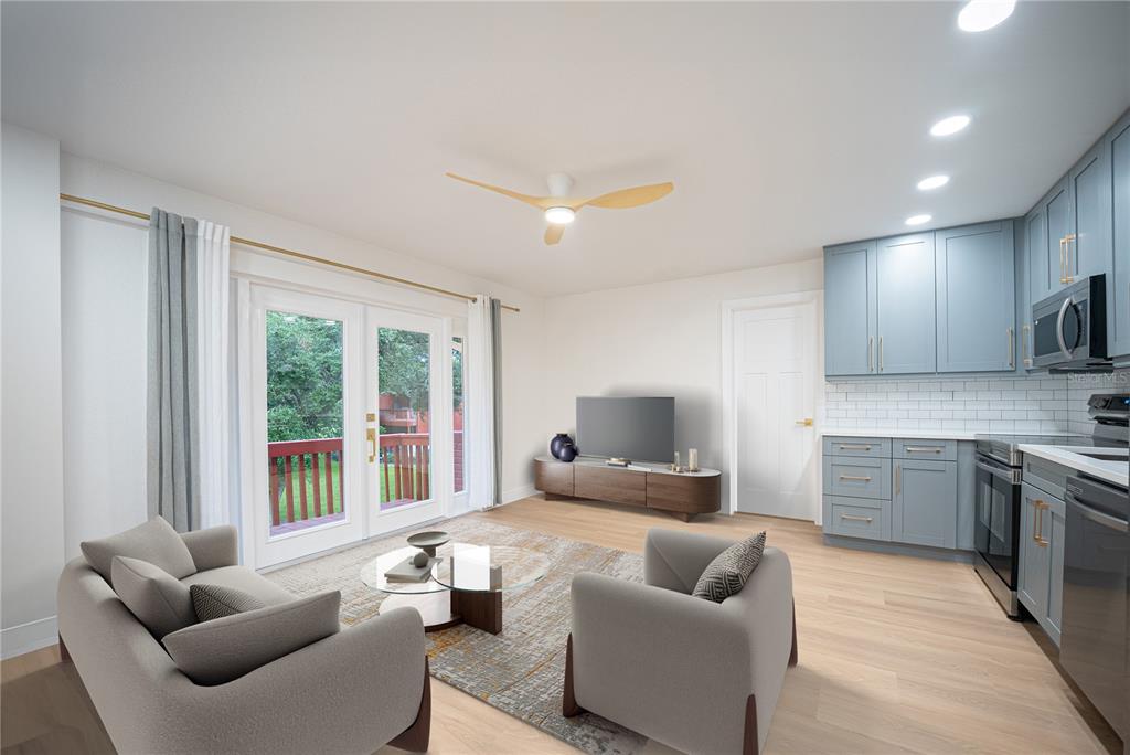 A living room with a kitchen, light wood floors, grey cabinets, and a balcony view — 8210 12TH WAY N UNIT G, ST PETERSBURG, FL