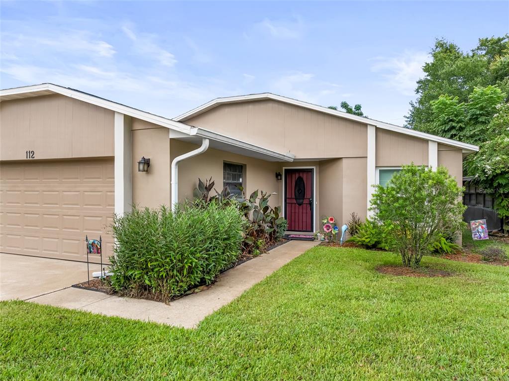 A single-story house with a tan exterior, a two-car garage, and a front walkway — 112 MAYFAIR CT, SANFORD, FL