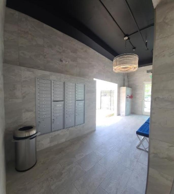 A modern mailroom features gray tiled walls, a black ceiling, a crystal chandelier, and mailboxes — 644 3RD AVENUE S UNIT 408, ST PETERSBURG, FL