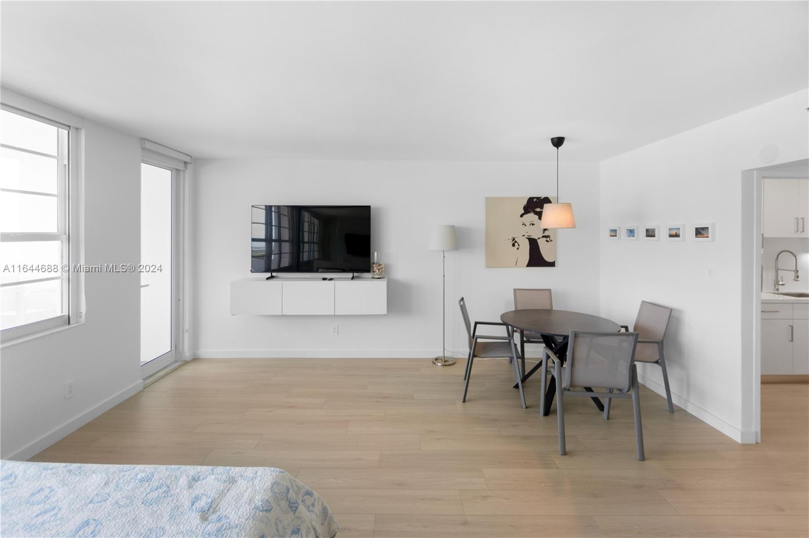 A bright living and dining area features light wood floors, a wall-mounted television, and furniture — 100 Lincoln Rd # 1104, Miami Beach FL 33139, MIAMI BEACH, FL