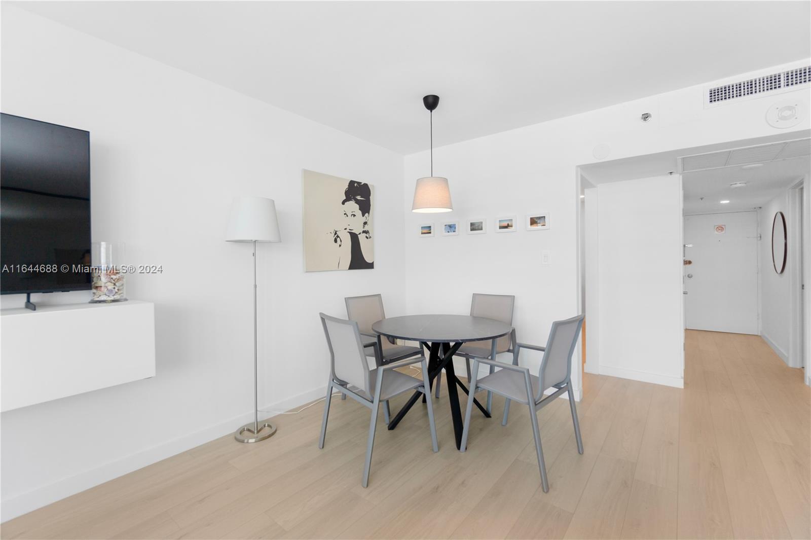 A dining area features a round table with four chairs, a pendant light, and artwork — 100 Lincoln Rd # 1104, Miami Beach FL 33139, MIAMI BEACH, FL