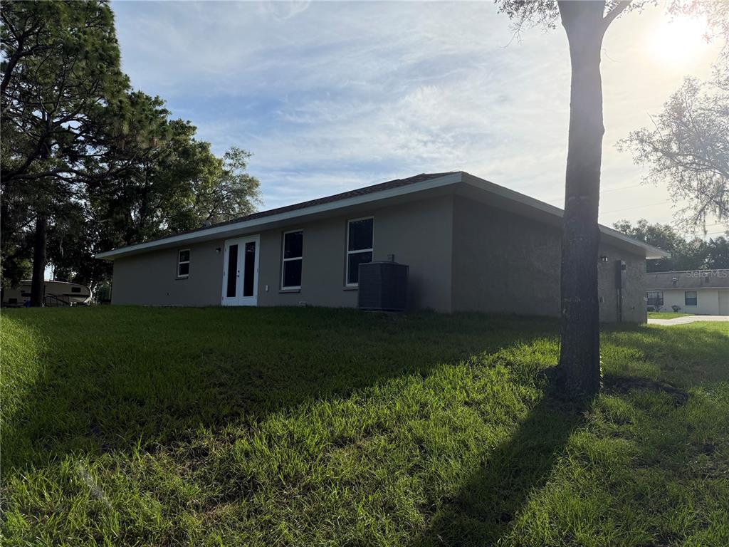 The exterior of a single-story house with a tan stucco finish and a grassy yard — 729 DRAKE AVENUE, INVERNESS, FL