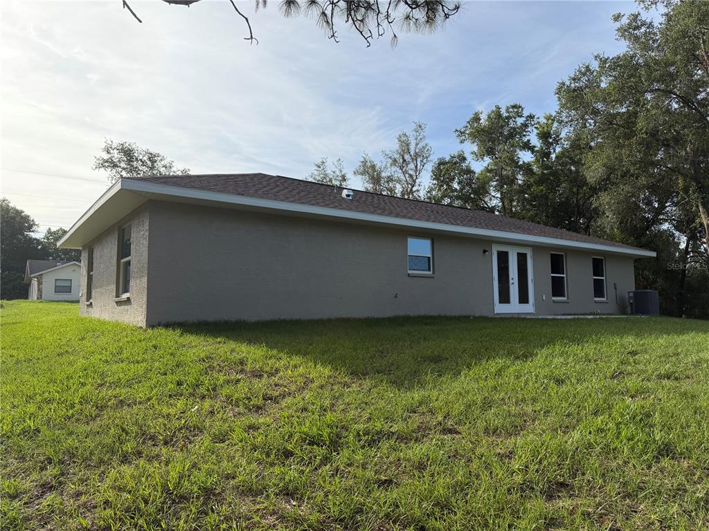 The exterior of a beige, single-story house features a shingled roof and a grassy yard — 729 DRAKE AVENUE, INVERNESS, FL