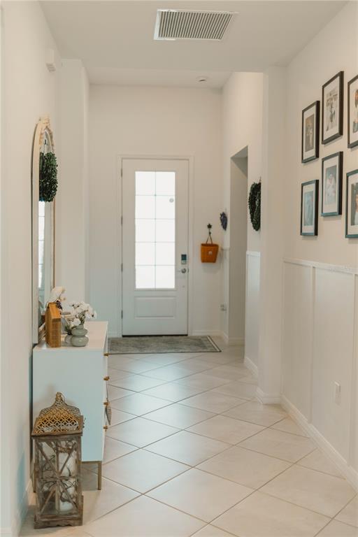A bright entryway features white walls, tile flooring, a front door, and a gallery wall — 1873 E ISLES ROAD, PORT CHARLOTTE, FL