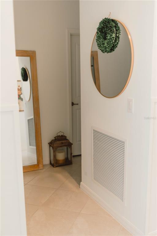 A hallway features a round mirror, a full-length floor mirror, and a decorative lantern — 1873 E ISLES ROAD, PORT CHARLOTTE, FL