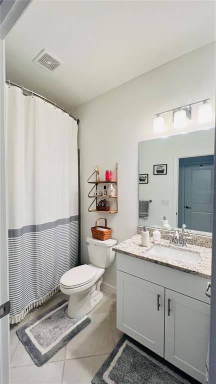 A bathroom features a white vanity, a toilet, a shower with a striped curtain, and shelving — 1873 E ISLES ROAD, PORT CHARLOTTE, FL