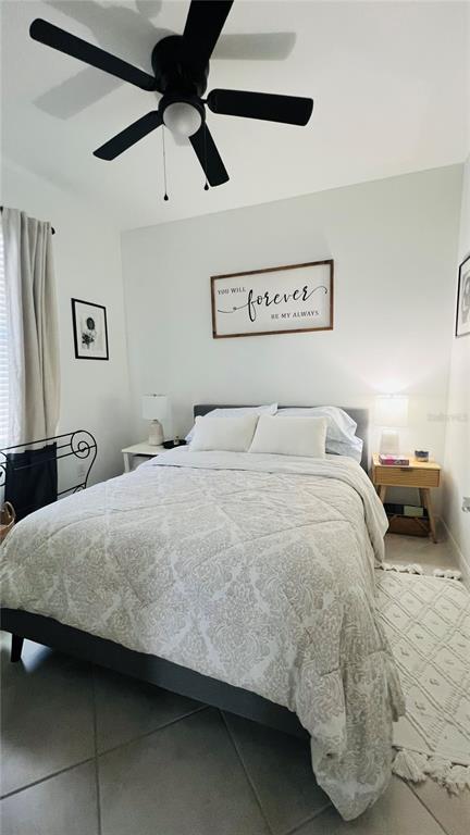 A bedroom features a bed with a patterned comforter, a ceiling fan, and wall decor — 1873 E ISLES ROAD, PORT CHARLOTTE, FL