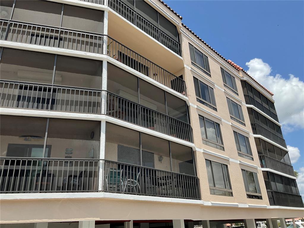 A multi-story apartment building features screened-in balconies and tan stucco exterior walls — 25188 MARION AVENUE UNIT D207, PUNTA GORDA, FL