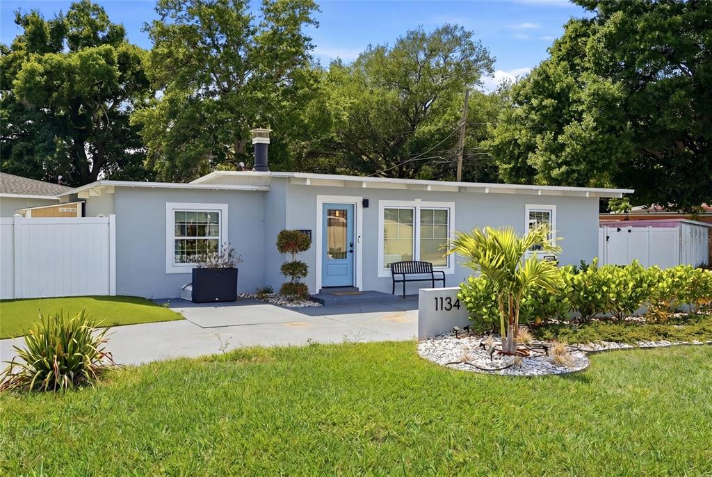 A single-story light gray house features a blue front door and a small front yard — 1134 MEADOWLAWN DRIVE N, ST PETERSBURG, FL