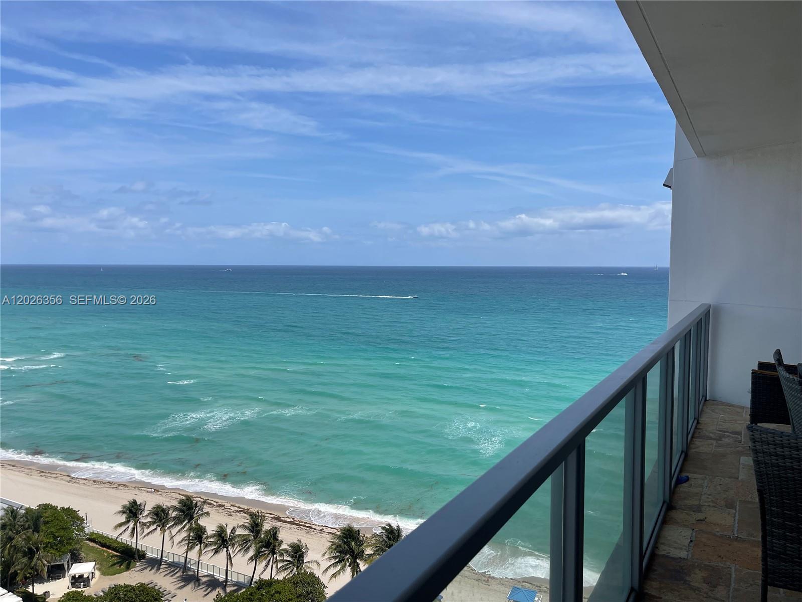 A balcony with a glass railing overlooks a sandy beach and the ocean — 3101 S Ocean Dr # 1707, Hollywood FL 33019, HOLLYWOOD, FL