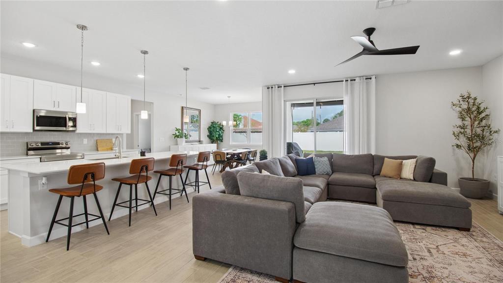An open-concept kitchen and living room featuring white cabinetry, a large sectional, and tile flooring — 61 BEAUFORD LANE, PALM COAST, FL