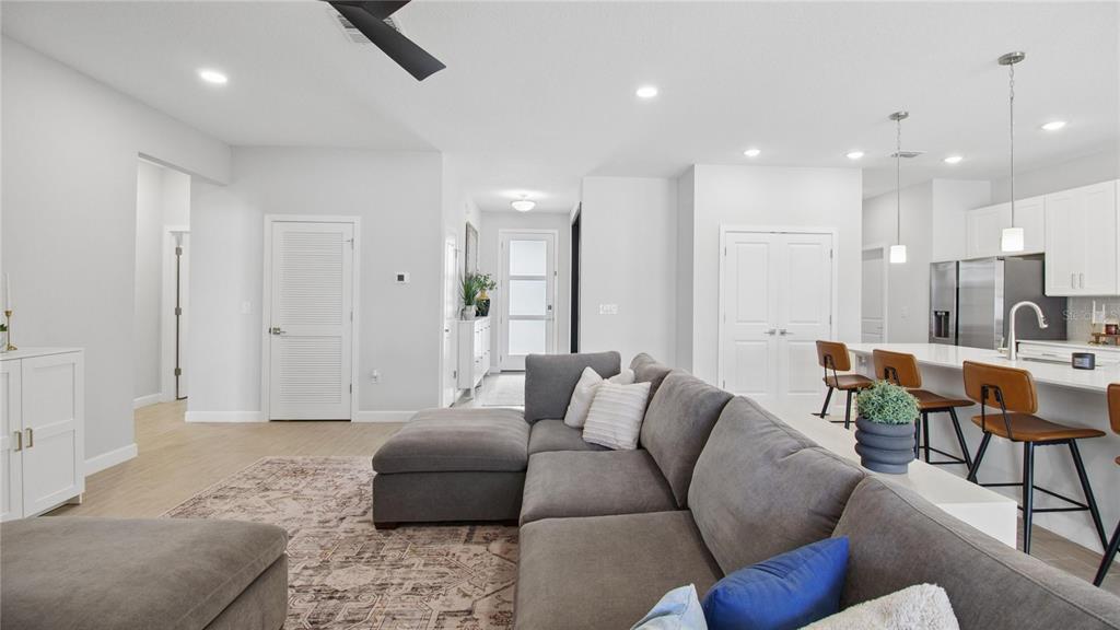 A modern open-concept living room features a grey sectional sofa, kitchen island, and white cabinetry — 61 BEAUFORD LANE, PALM COAST, FL
