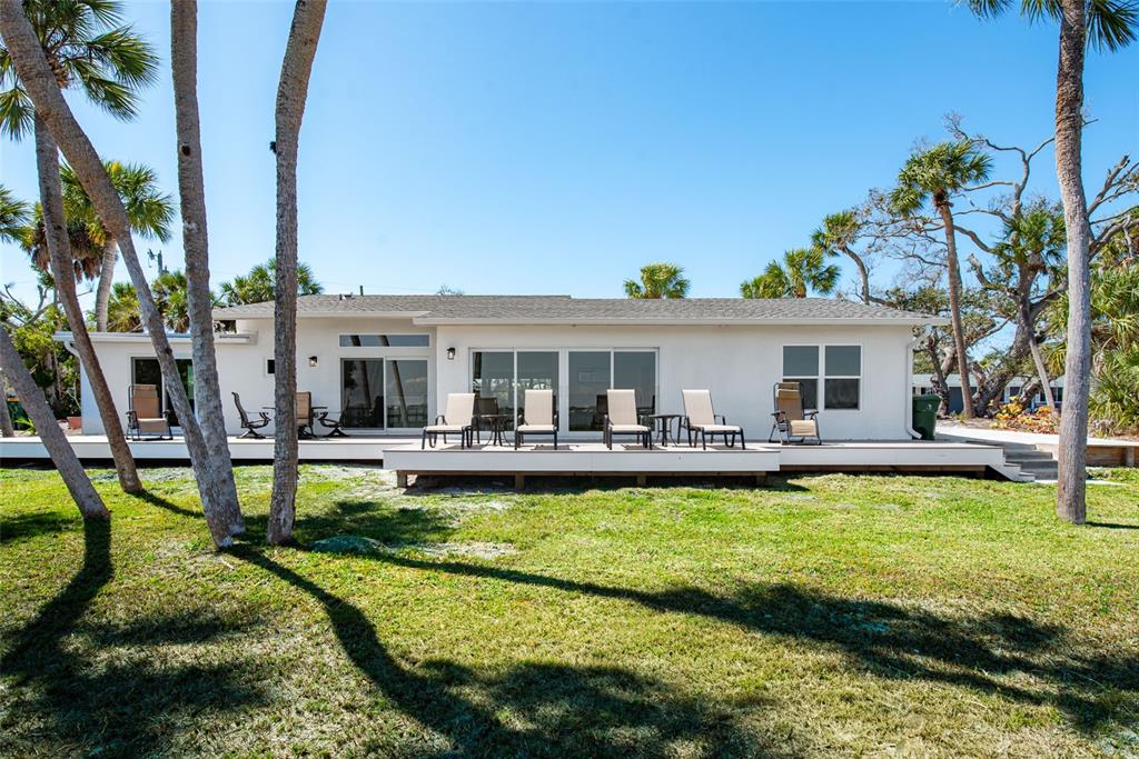 The exterior of a white house features a large wooden deck with several patio chairs — 4087 PELICAN SHORES CIRCLE, ENGLEWOOD, FL