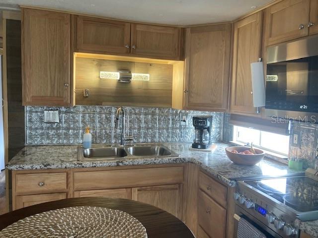 A kitchen features oak cabinets, a tiled backsplash, a small dining table, and stainless appliances — 800 32ND AVENUE S UNIT 227, ST PETERSBURG, FL