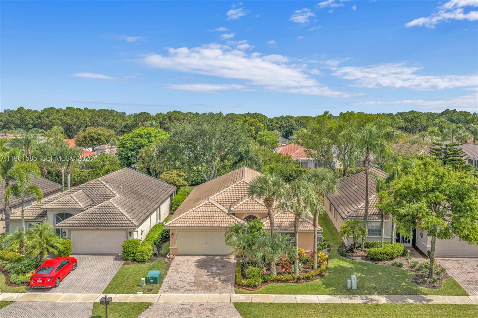 An aerial view shows three suburban houses with tiled roofs and landscaped front yards — 8046 Duomo Cir, Boynton Beach FL 33472, BOYNTON BEACH, FL