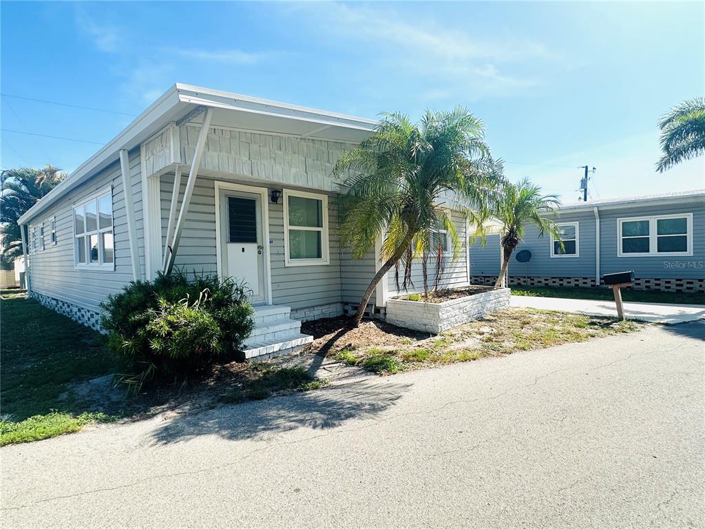 A light gray manufactured home with a palm tree and a small front porch — 147 MAUI DRIVE, PALMETTO, FL