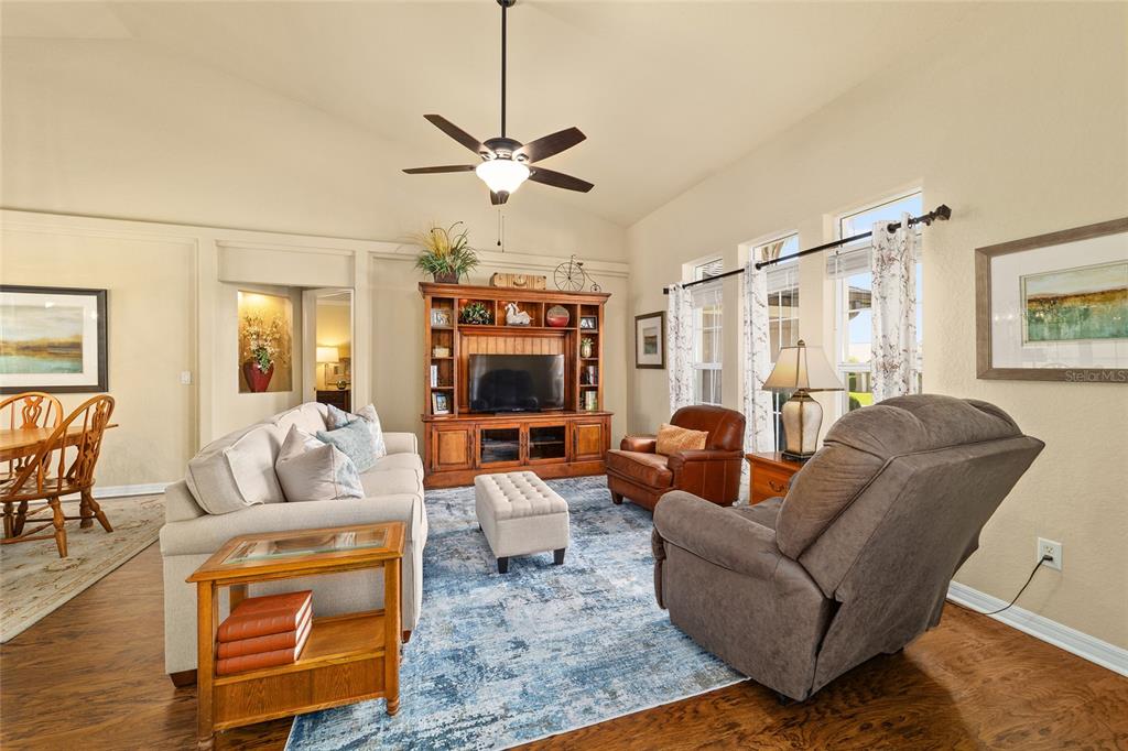 A living room features a vaulted ceiling, a wooden entertainment center, and a blue rug — 4615 SE 35TH PLACE, OCALA, FL