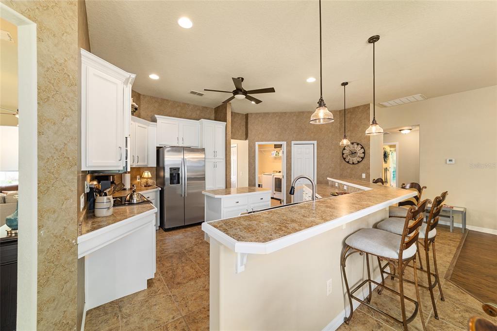 A kitchen featuring white cabinets, stainless steel appliances, a breakfast bar, and tile flooring — 4615 SE 35TH PLACE, OCALA, FL
