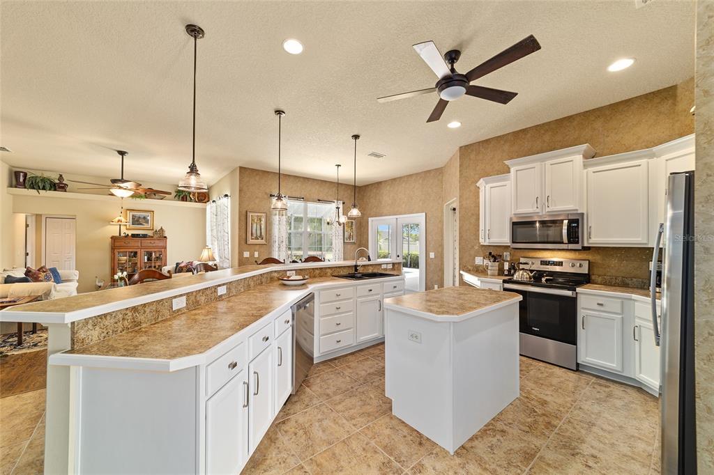 A kitchen with white cabinets, tan countertops, a center island, and tile flooring — 4615 SE 35TH PLACE, OCALA, FL