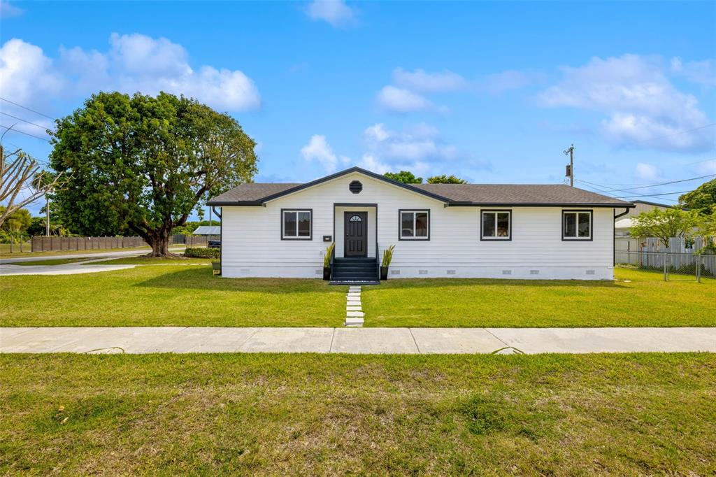 A single-story white house with a dark roof and front door sits on a lawn — 1867 NW 8TH AVENUE, HOMESTEAD, FL