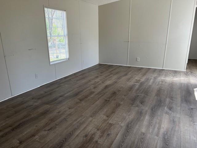 An empty room features light-colored paneled walls, a single window, and dark wood-look flooring — 65 SE 153 AVENUE, OLD TOWN, FL