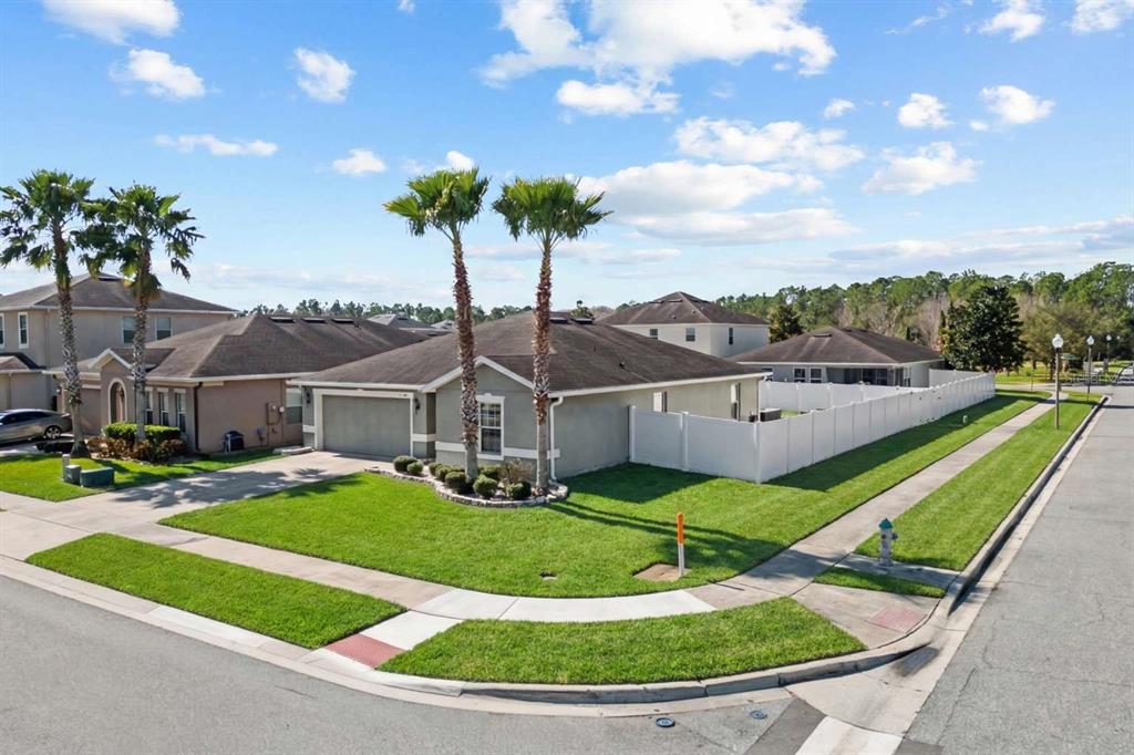 A single-story house with a two-car garage, palm trees, and a white vinyl privacy fence — 10502 BULL GRASS DRIVE, ORLANDO, FL