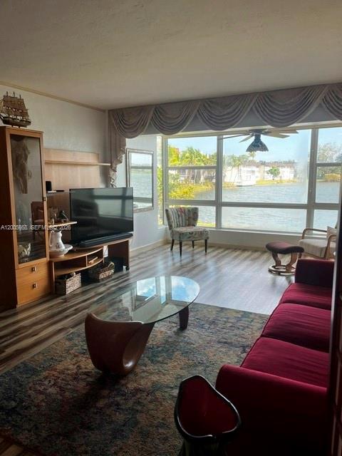 A living room features a red sofa, glass coffee table, and large windows overlooking water — 18901 NE 14th Ave # 101, Miami FL 33179, MIAMI, FL