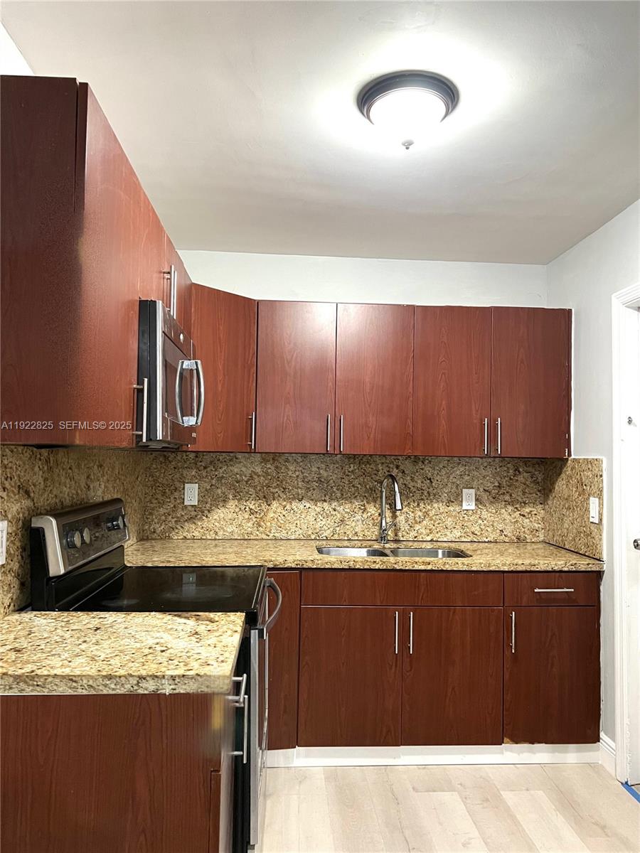 A kitchen features dark wood cabinets, granite countertops, and stainless steel appliances — 9710 SW SW 161 ST, Miami FL 33157, MIAMI, FL