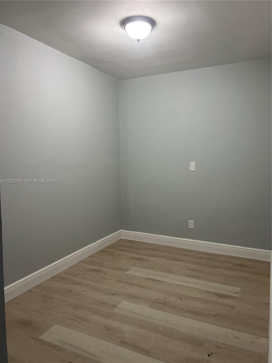 A small, empty room features light gray walls, white baseboards, and light-colored wood-look flooring — 9710 SW SW 161 ST, Miami FL 33157, MIAMI, FL