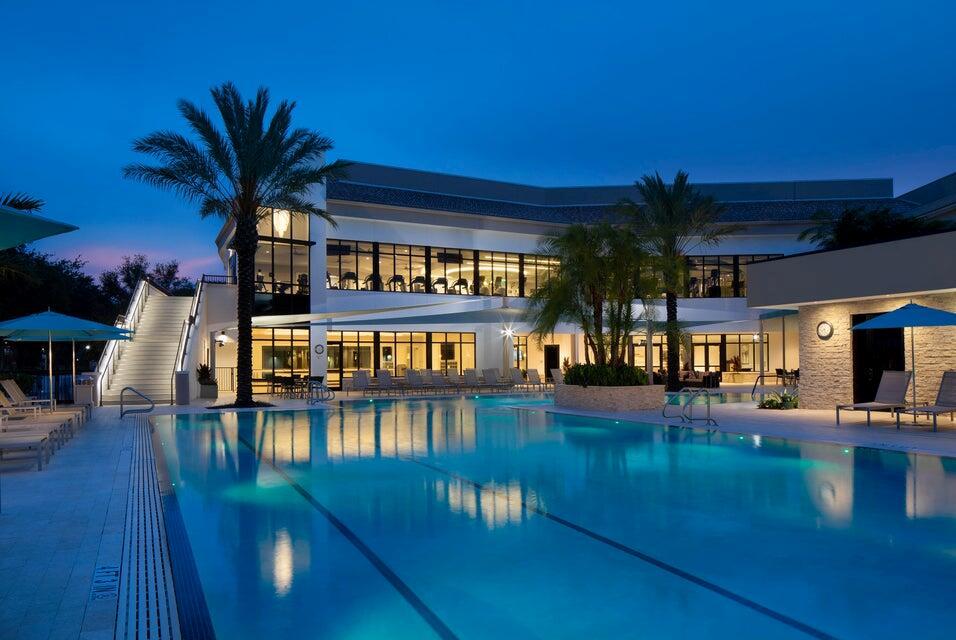 A swimming pool sits in front of a modern building with a staircase at dusk — 16021 Loch Katrine Trail # 7405, Delray Beach FL 33446, DELRAY BEACH, FL