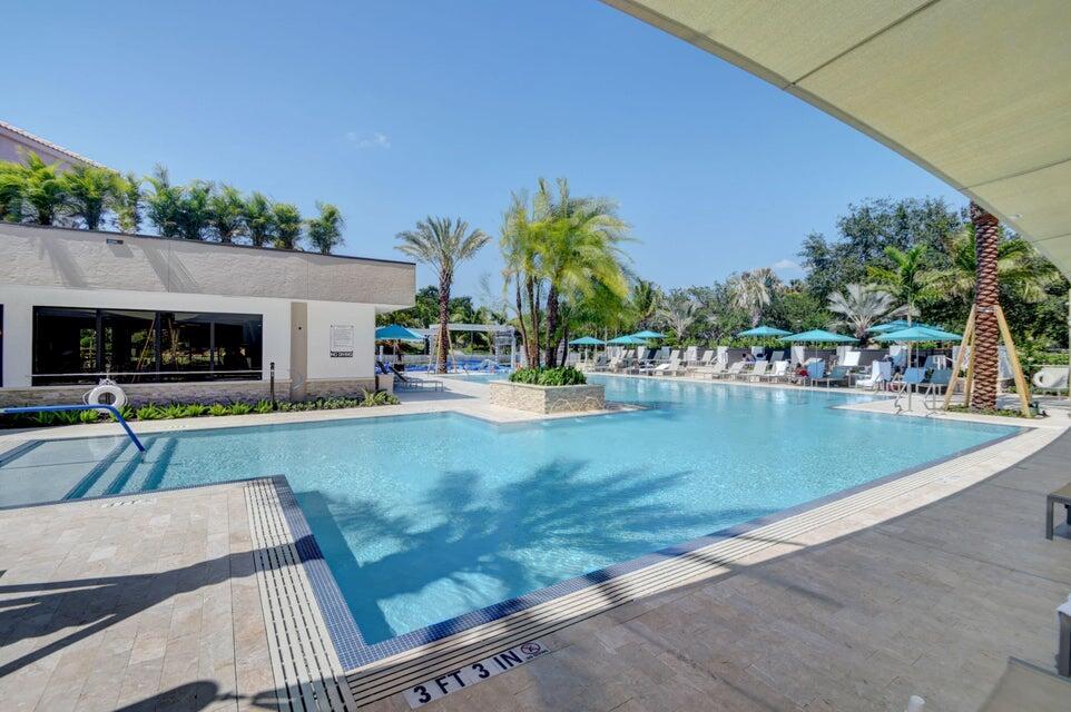 A swimming pool with a central palm tree planter and lounge chairs under umbrellas — 16021 Loch Katrine Trail # 7405, Delray Beach FL 33446, DELRAY BEACH, FL