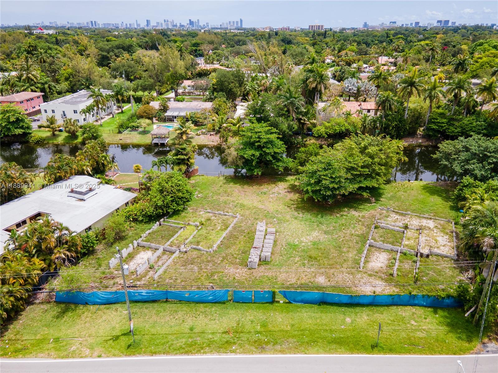 An aerial view shows a vacant lot with concrete foundation footings and a canal behind — 11595 W Biscayne Canal Rd, Miami FL 33161, MIAMI, FL