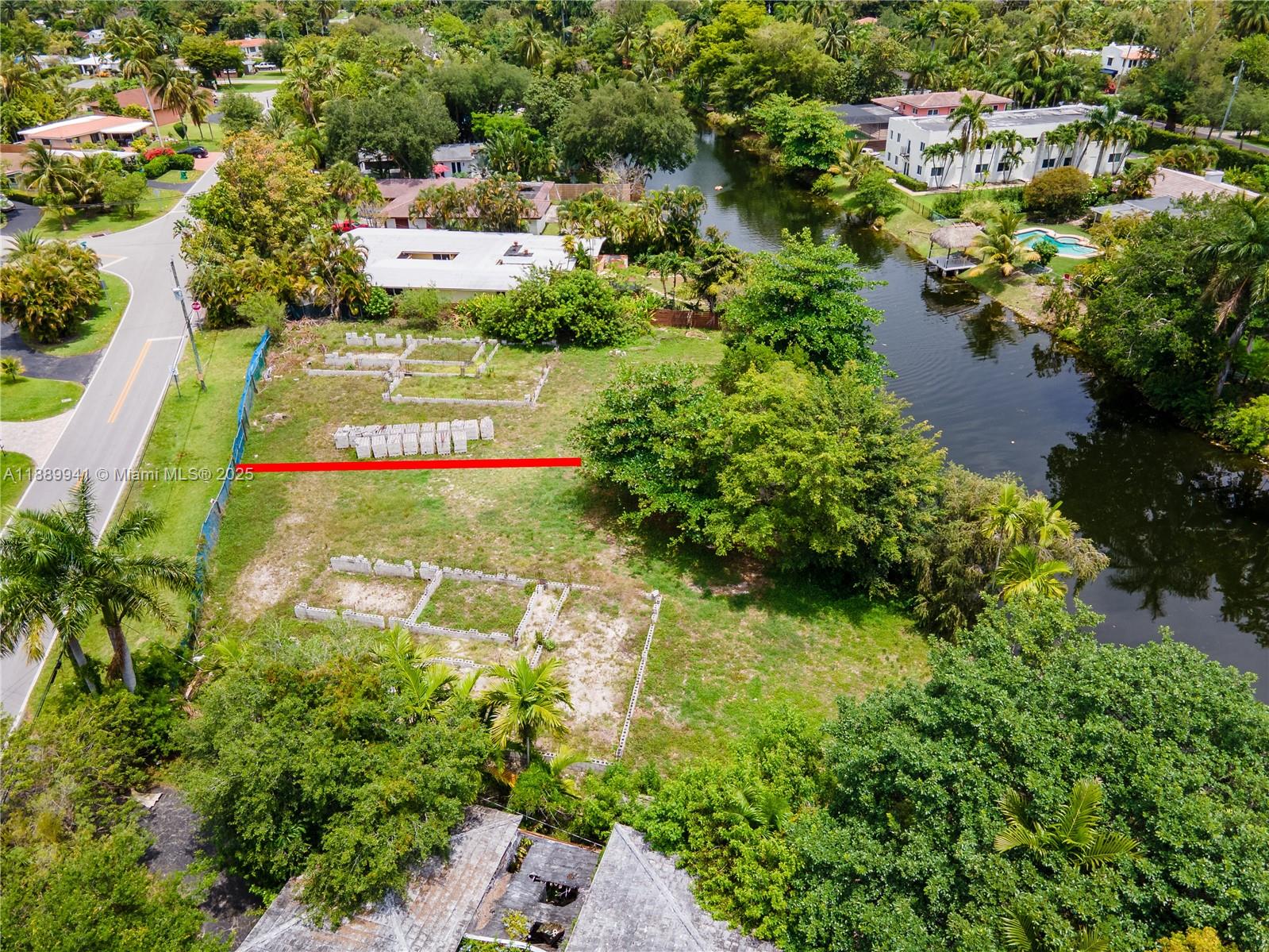 An aerial view shows a vacant waterfront lot with concrete foundation outlines and scattered blocks — 11595 W Biscayne Canal Rd, Miami FL 33161, MIAMI, FL