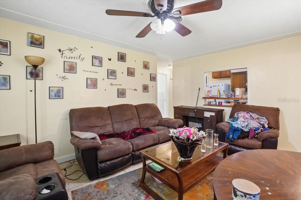 A living room features brown sofas, a coffee table, and a wall decorated with photos — 526 12TH AVENUE S, ST PETERSBURG, FL
