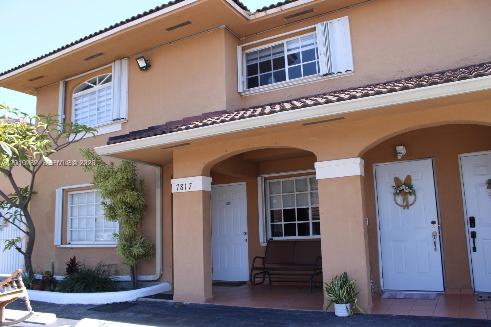 The exterior of a two-story tan stucco building features a covered porch and tiled roof — 7817 W 36th Ave # 204, Hialeah FL 33018, HIALEAH, FL