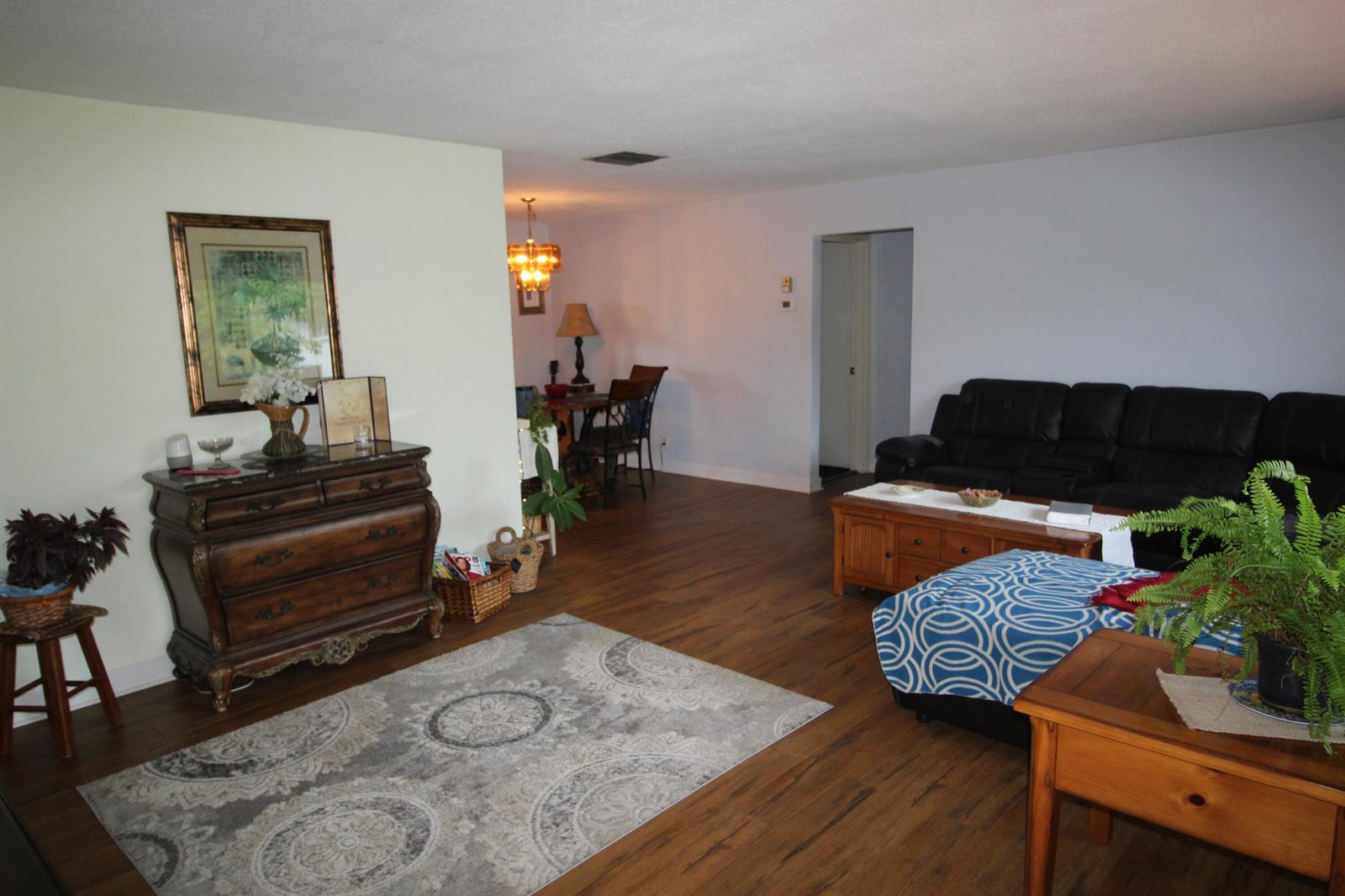 A living room with wood-look flooring, a dark leather sofa, and an ornate wooden dresser — 4914 NW 49th Road, Tamarac FL 33319, TAMARAC, FL
