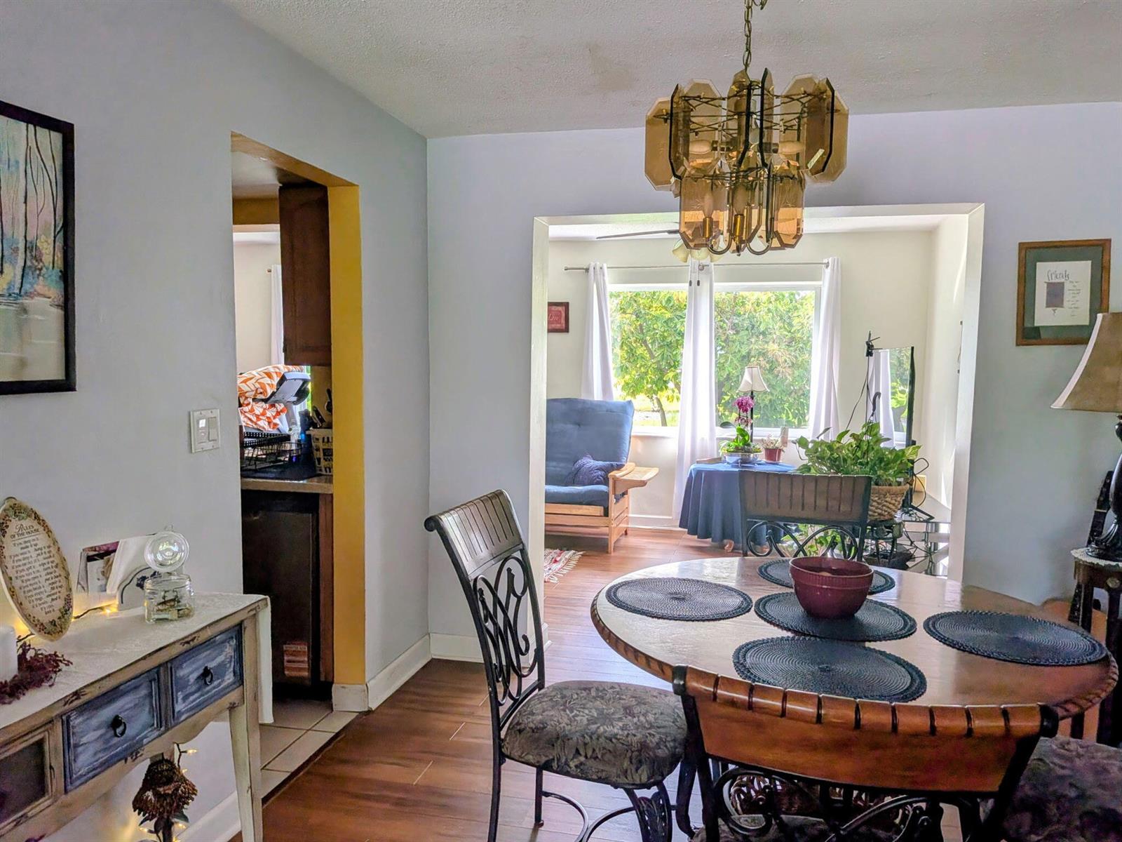 A dining area with a round wooden table, metal chairs, and a vintage glass chandelier — 4914 NW 49th Road, Tamarac FL 33319, TAMARAC, FL