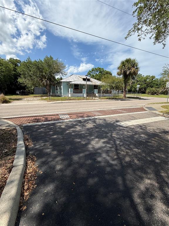 A light blue house with a metal roof sits behind a brick-paved crosswalk — 585 WASHINGTON STREET, NEW SMYRNA BEACH, FL