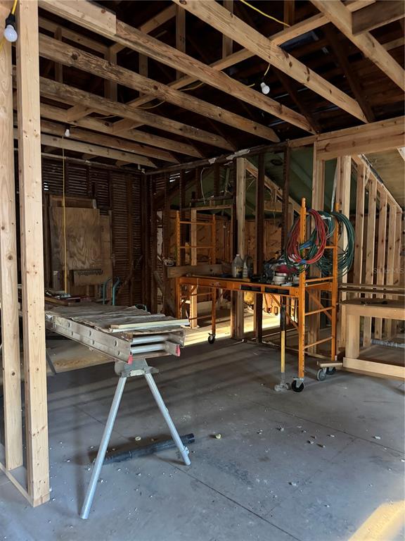 An unfinished room under renovation features exposed wooden framing, a metal scaffold, and concrete flooring — 585 WASHINGTON STREET, NEW SMYRNA BEACH, FL
