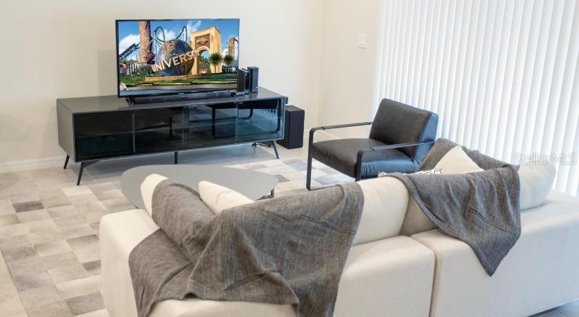 A living room features a white sectional sofa, a black armchair, and a media console — 8879 GENEVE COURT, KISSIMMEE, FL