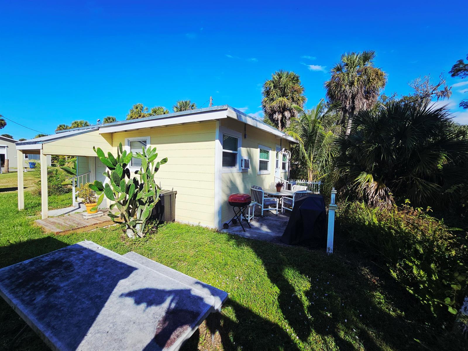 A yellow cottage with a patio, outdoor seating, a grill, and a large cactus — 1087 Dusty Lane, Moore Haven FL 33471, MOORE HAVEN, FL