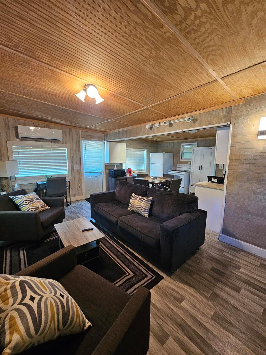 A living room with dark gray furniture, wood-paneled ceilings, and an open kitchen area — 1087 Dusty Lane, Moore Haven FL 33471, MOORE HAVEN, FL