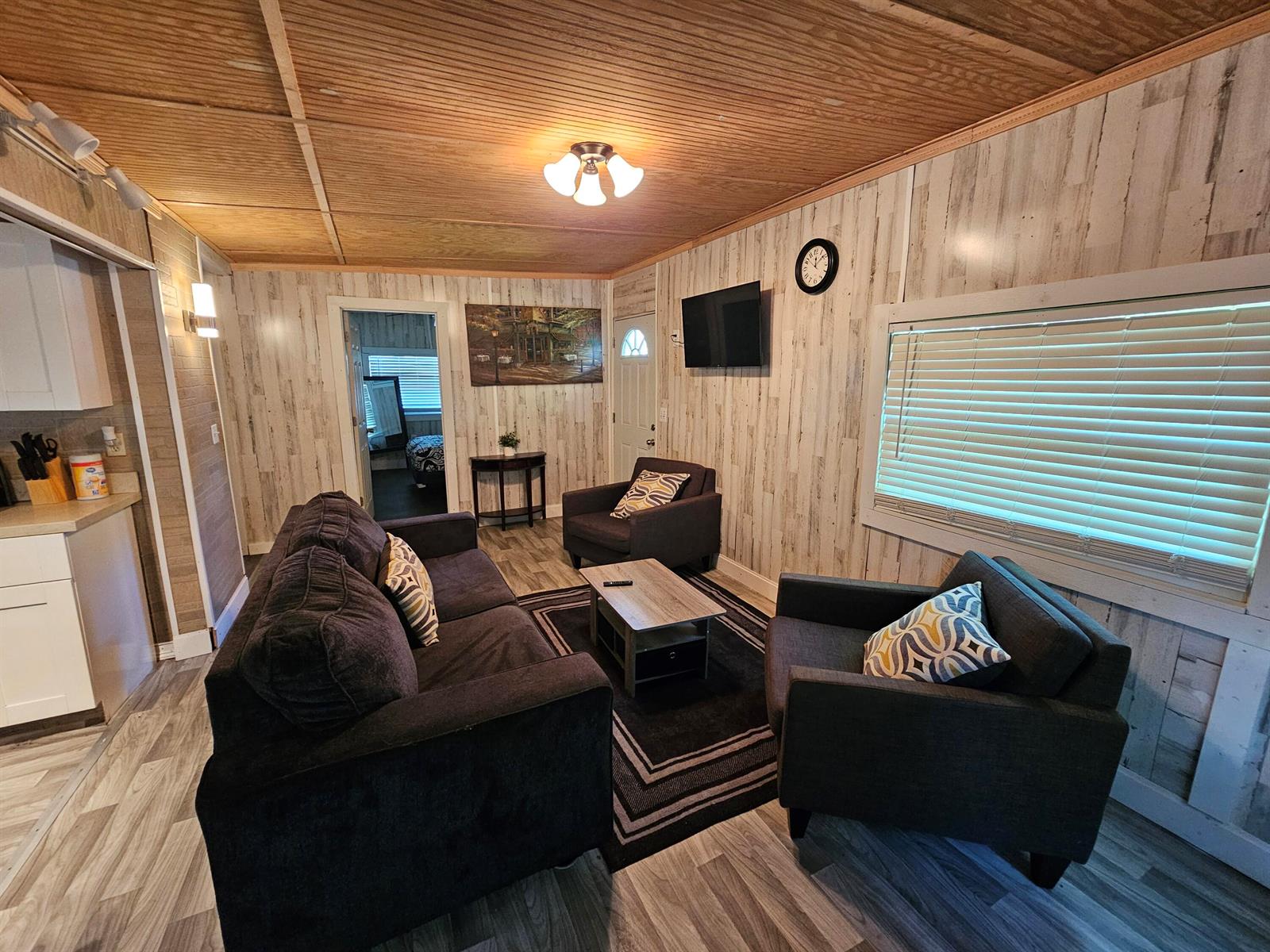 A living room features wood-paneled walls and ceilings, dark upholstered furniture, and a coffee table — 1087 Dusty Lane, Moore Haven FL 33471, MOORE HAVEN, FL