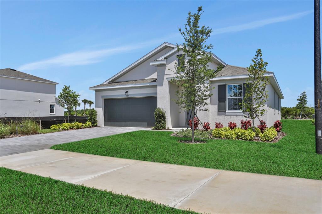 A single-story house with a gray garage, light stucco exterior, and a landscaped front yard — 13494 TURNLEAF BOULEVARD, PUNTA GORDA, FL