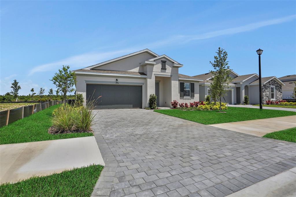 A single-story house with a gray garage, paver driveway, and landscaped front yard — 13494 TURNLEAF BOULEVARD, PUNTA GORDA, FL
