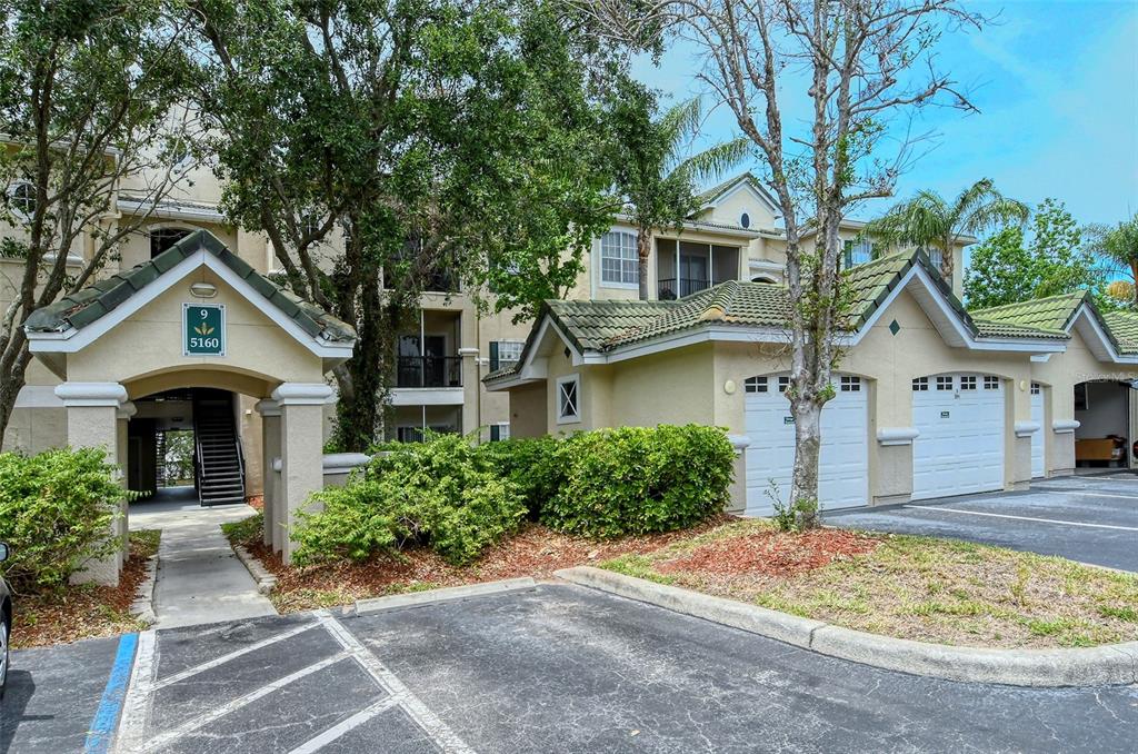 An exterior view of a multi-story apartment building with attached garages and a covered entrance — 5160 NORTHRIDGE ROAD UNIT 107, SARASOTA, FL